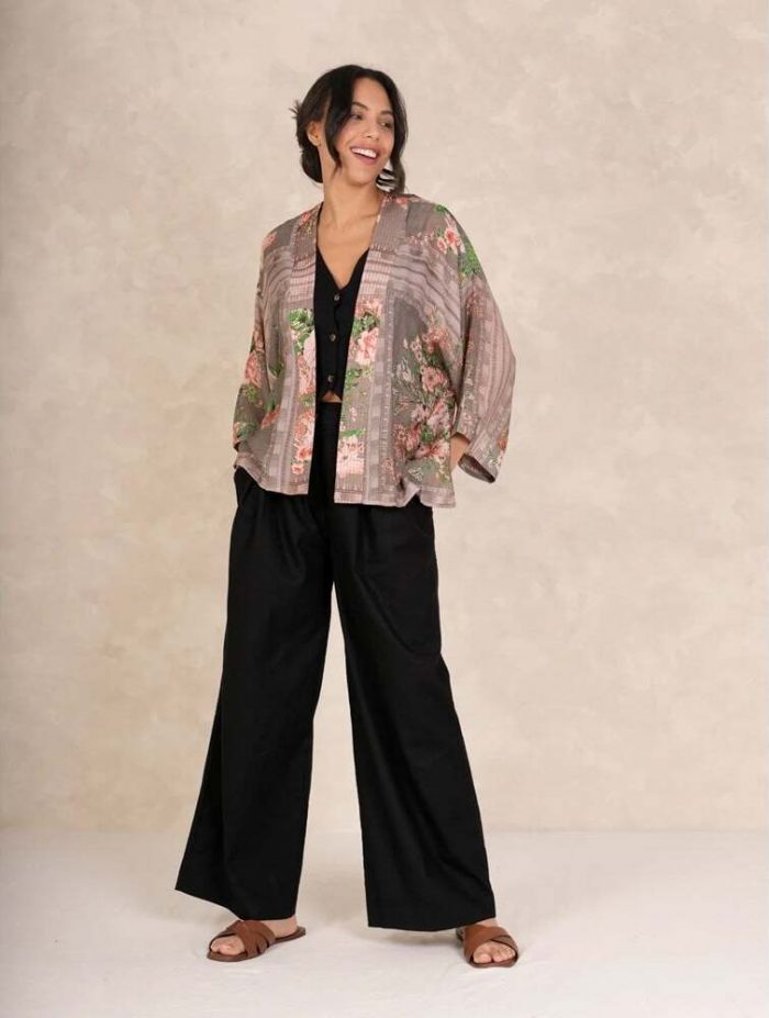 How to dress up a kimono​. Woman wearing a pink floral One Hundred Stars kimono with a black waistcoat and black trousers. 